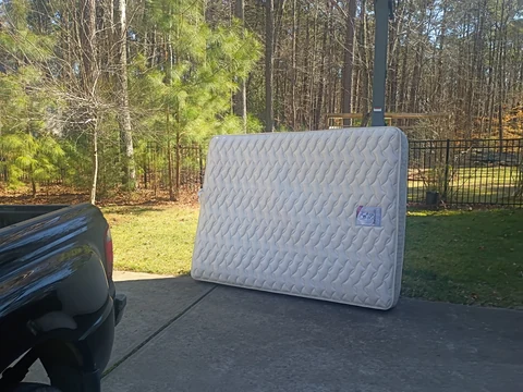 Customer photo: a mattress standing outside on a driveway before removal.